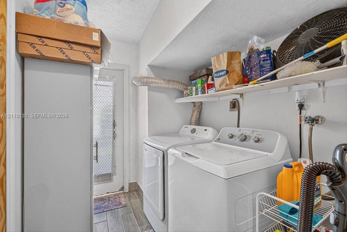 Laundry area featuring wood-finish tile flooring, white-finish wall-mounted shelving, and a metal-frame exterior door