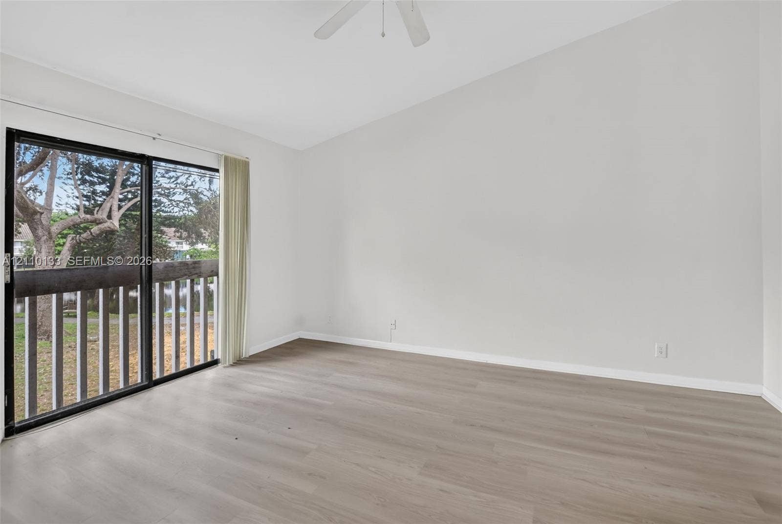 7890 Lago Del Mar Drive, #141, Boca Raton, Boca Raton, FL 33433 Interior space featuring vaulted ceilings, wood-finish flooring, a ceiling fan, and sliding glass doors with access to an exterior balcony