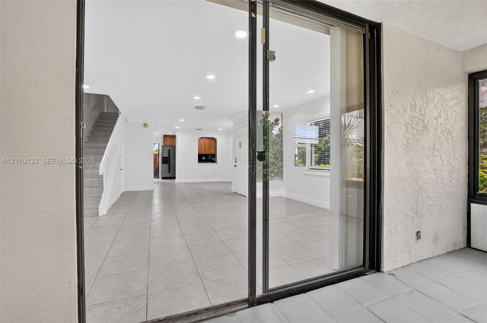 7890 Lago Del Mar Drive, #141, Boca Raton, Boca Raton, FL 33433 Sliding glass doors with black frames, neutral tile flooring, recessed lighting, and a built-in arched wall opening