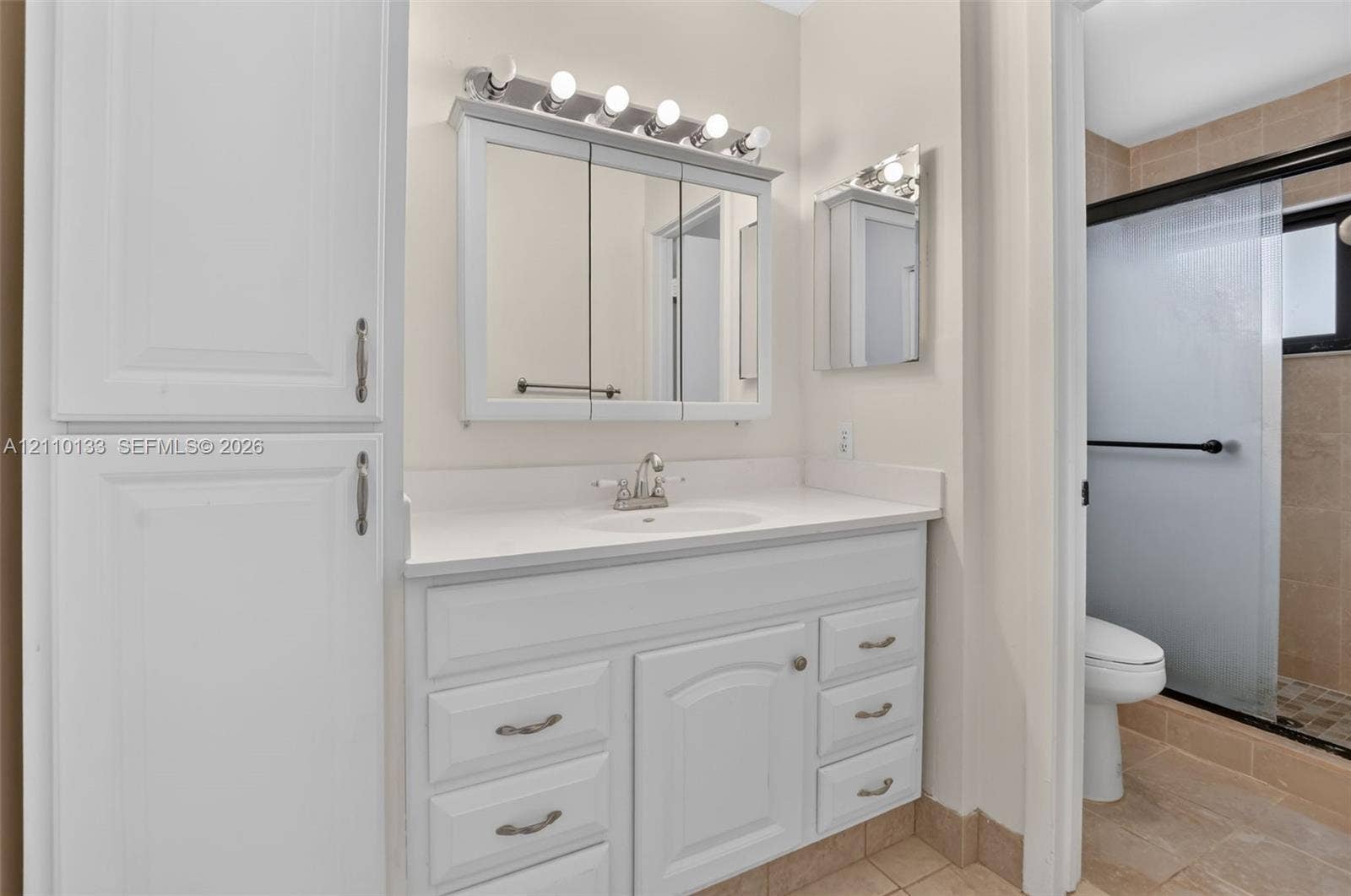 7890 Lago Del Mar Drive, #141, Boca Raton, Boca Raton, FL 33433 Bathroom featuring a white vanity with integrated cabinetry, solid surface countertop, tri-fold medicine cabinet, and a glass-enclosed shower with tiled surround