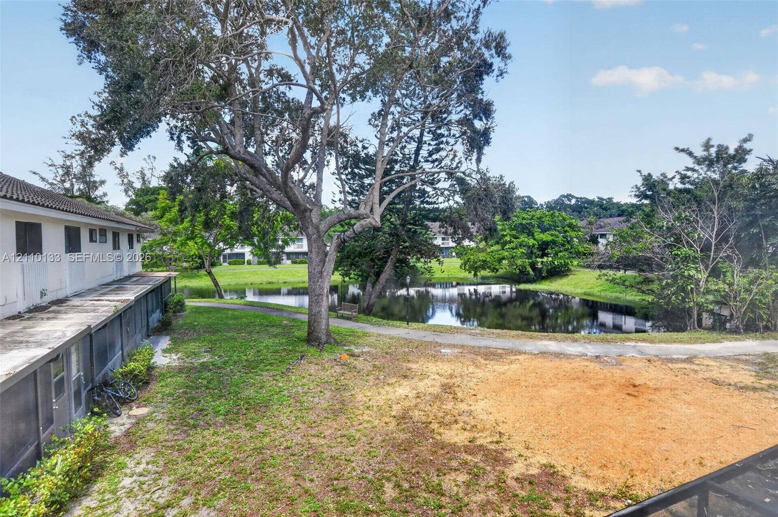 7890 Lago Del Mar Drive, #141, Boca Raton, Boca Raton, FL 33433 Exterior grounds featuring a paved pathway, mature trees, and a water feature