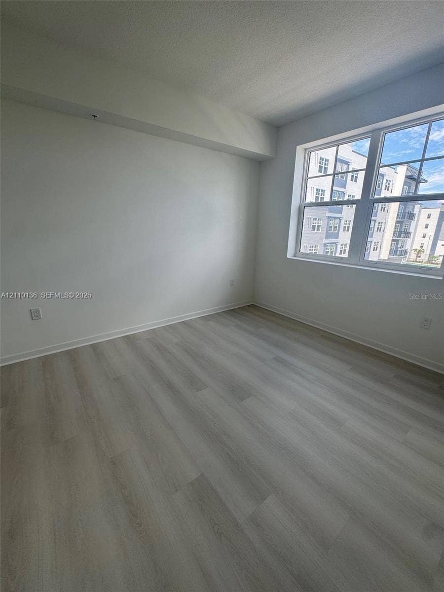 5563 Millenia Park Boulevard, #328, Orlando, Orlando, FL 32839 Interior room featuring light-toned wood-finish flooring, neutral walls, and a large multi-pane window