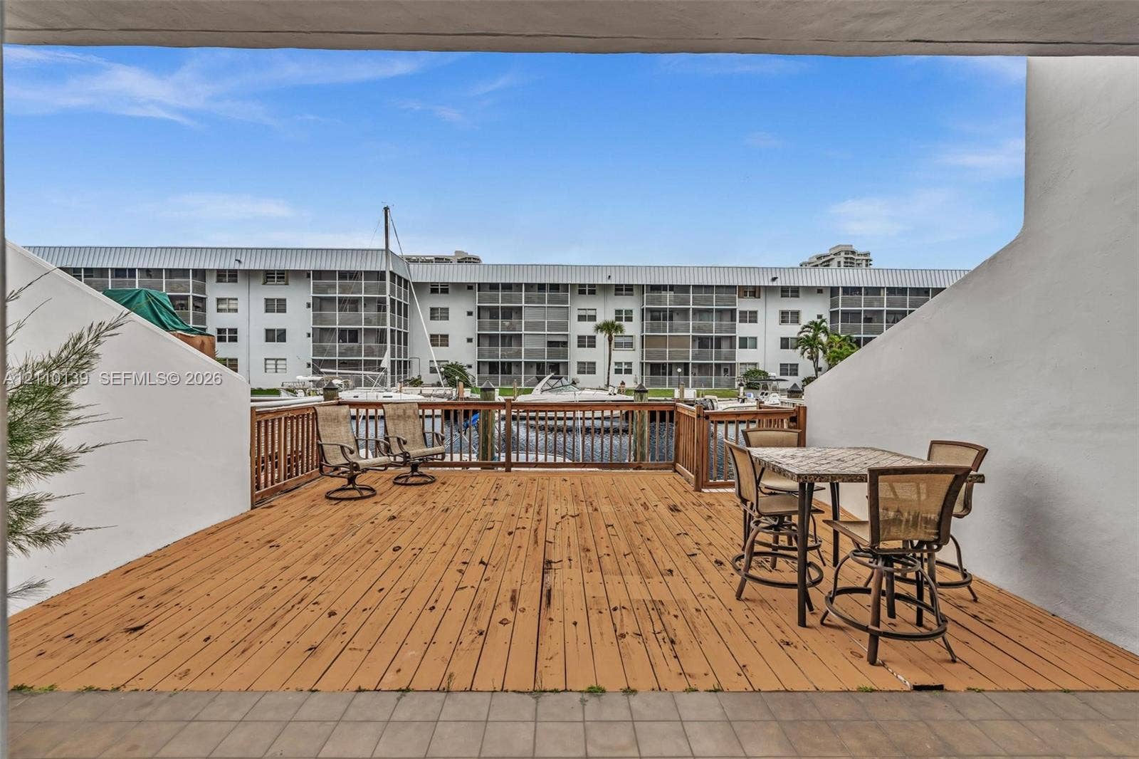 3601 NE 168th Street, #108, North Miami Beach, FL 33160 Covered exterior deck with wood-finish decking and perimeter wood railing, situated over water