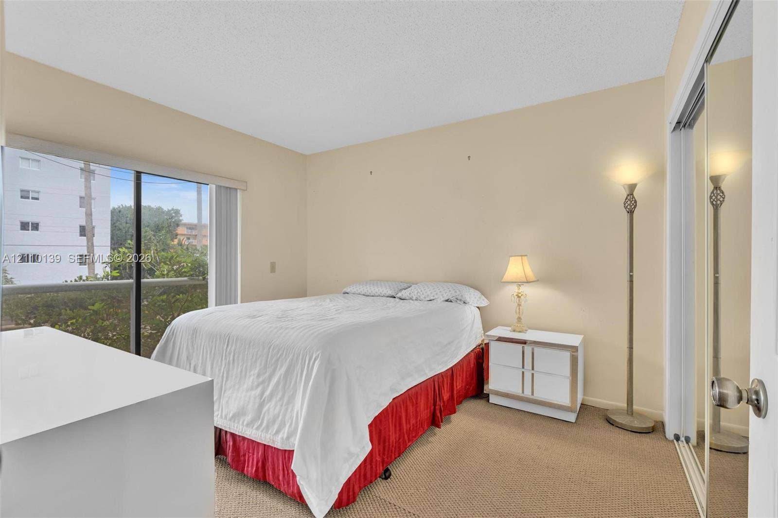 3601 NE 168th Street, #108, North Miami Beach, FL 33160 Floor-to-ceiling sliding glass door, carpeted flooring, and mirrored closet doors