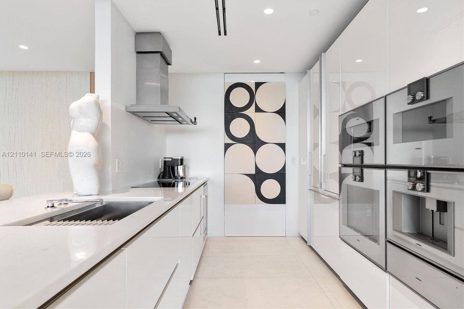 10203 Collins Avenue, #303, Bal Harbour, FL 33154 High-gloss cabinetry, integrated stainless steel appliances, recessed ceiling lighting, stone-finish countertops, and a seamless sink basin
