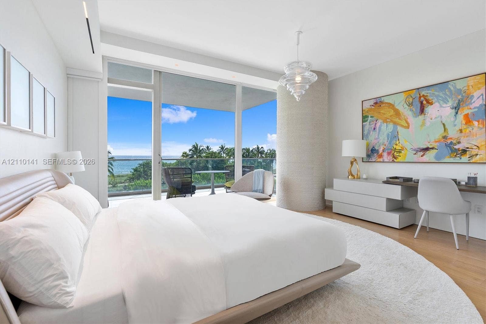 10203 Collins Avenue, #303, Bal Harbour, FL 33154 Floor-to-ceiling glass doors, wood-finish flooring, cylindrical architectural column with textured finish, pendant light fixture, and glass-railed private balcony