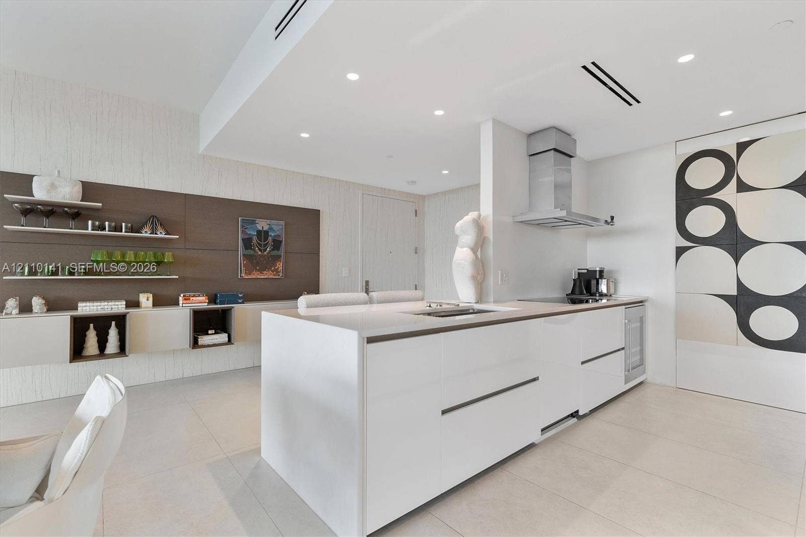 10203 Collins Avenue, #303, Bal Harbour, FL 33154 Modern kitchen featuring a central island with countertop, sleek handle-less cabinetry, stainless steel range hood, recessed ceiling lighting, and tile flooring