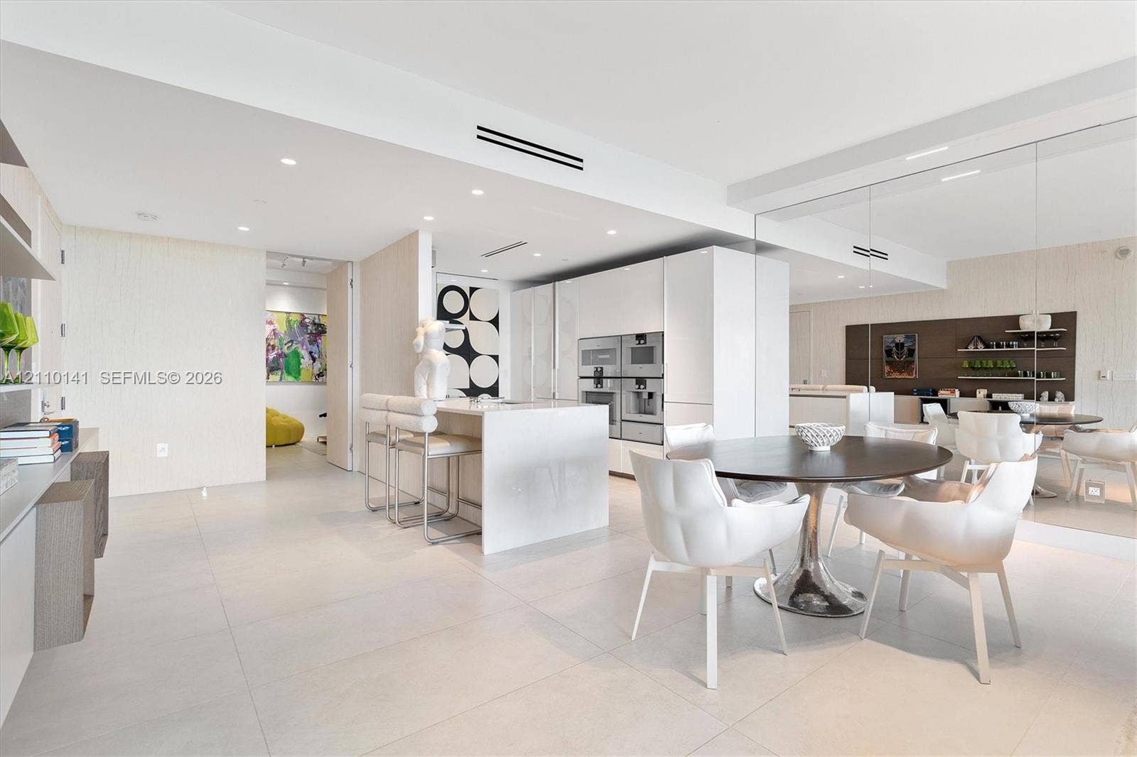 10203 Collins Avenue, #303, Bal Harbour, FL 33154 Contemporary kitchen featuring white slab-panel cabinetry, a central island with integrated stone waterfall-edge countertop, Large pantry