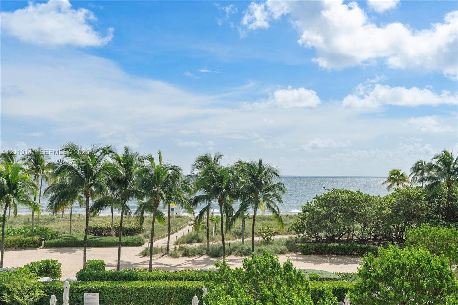 10203 Collins Avenue, #303, Bal Harbour, FL 33154 Coastal property featuring an expansive ocean horizon, mature palm trees, manicured hedges, and a private sand path leading to the beach. THE RESIDENCE IS A CORNER UNIT