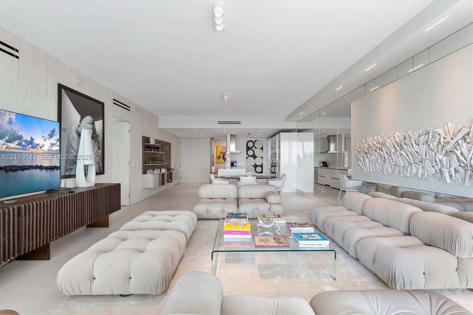 10203 Collins Avenue, #303, Bal Harbour, FL 33154 Open-concept interior featuring smooth solid-surface flooring, full-wall mirrored accents, recessed ceiling lighting, and custom linear built-in cabinetry