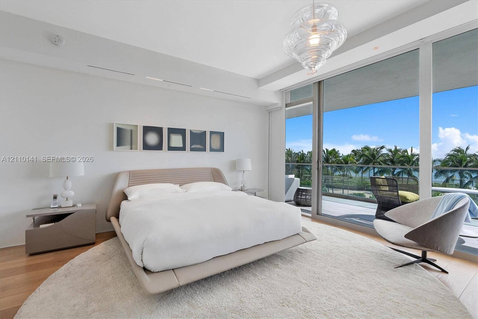 10203 Collins Avenue, #303, Bal Harbour, FL 33154 Floor-to-ceiling sliding glass doors, private balcony, wood-finish flooring, recessed lighting, and sculptural glass pendant fixture