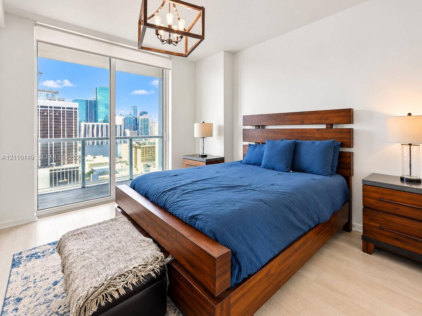 Floor-to-ceiling sliding glass door, private balcony, wood-finish flooring, and geometric-frame pendant lighting