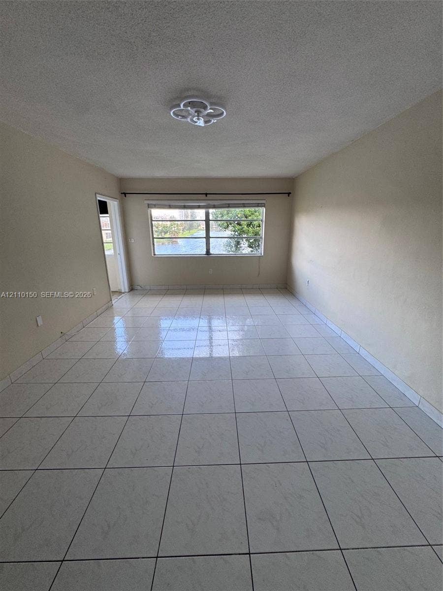 20111 NE 27th Court, #K212, Aventura, Aventura, FL 33180 Neutral-toned interior space featuring light-colored square tile flooring and a ceiling-mounted flush light fixture