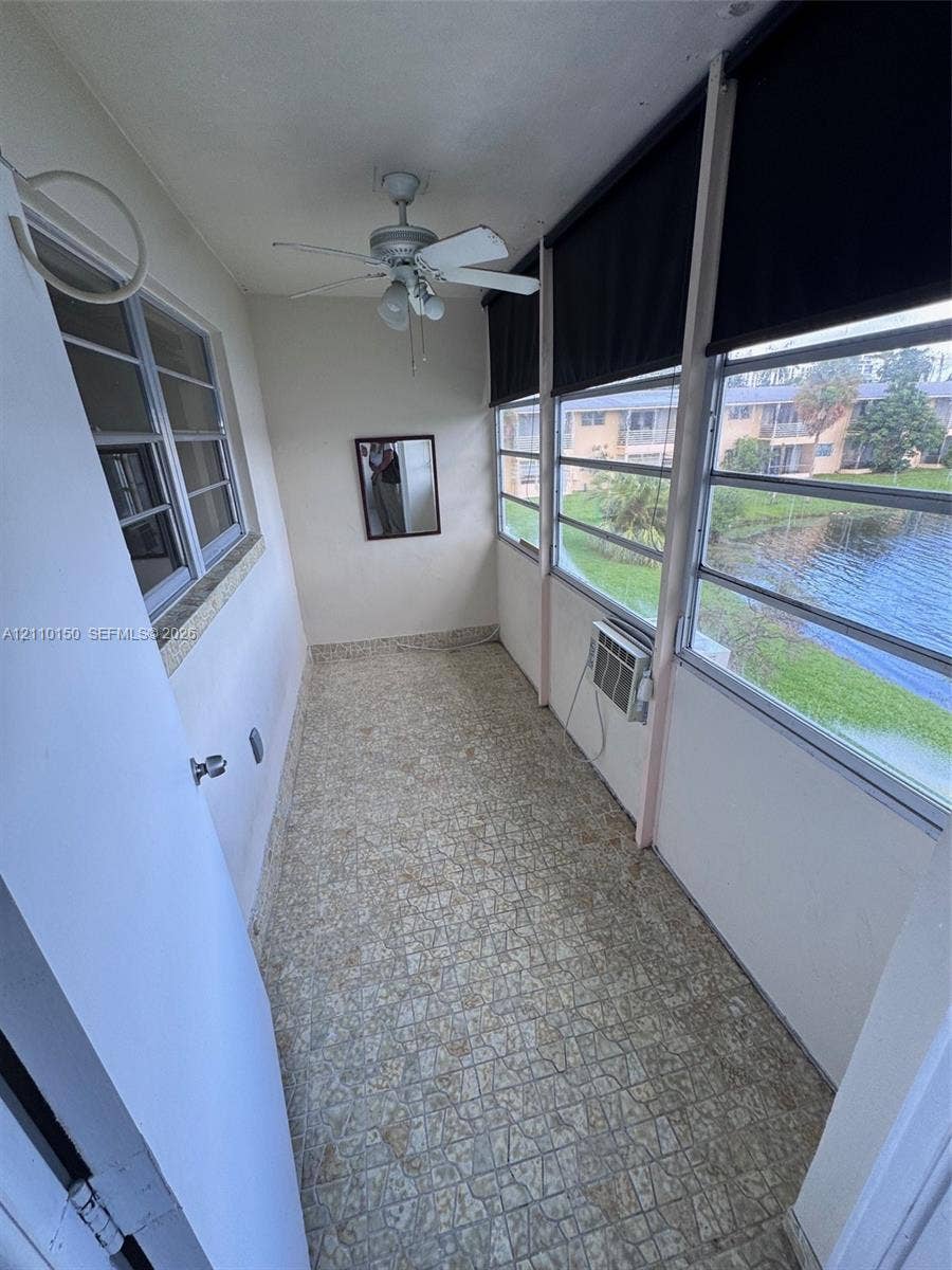 20111 NE 27th Court, #K212, Aventura, Aventura, FL 33180 Enclosed porch featuring patterned tile flooring, a ceiling fan with integrated lighting, and multiple windows overlooking a pond