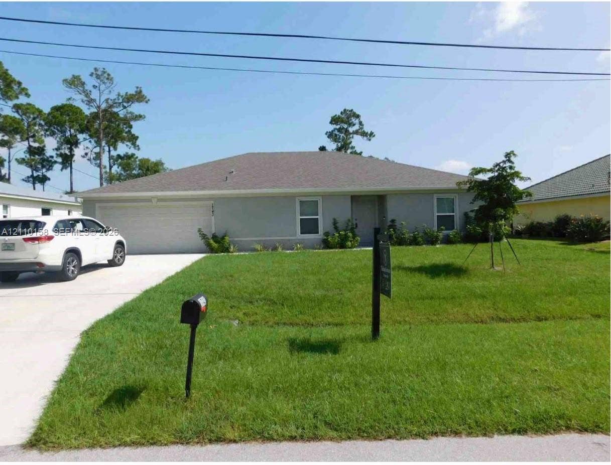 1743 SW Bellevue Avenue, Port St Lucie, FL 34953 Single-story residence featuring a light-toned stucco exterior, hip roof, concrete driveway, and attached two-car garage