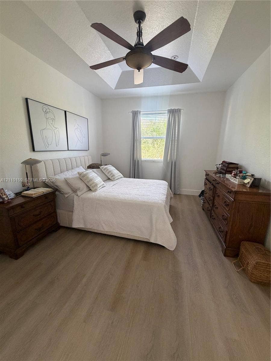 Tray ceiling with an integrated multi-blade ceiling fan and wood-finish flooring