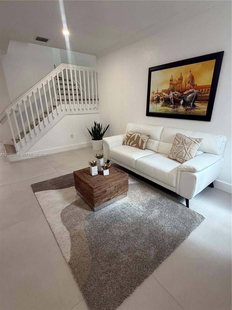 Neutral large-format tile flooring and staircase with white wooden balustrade