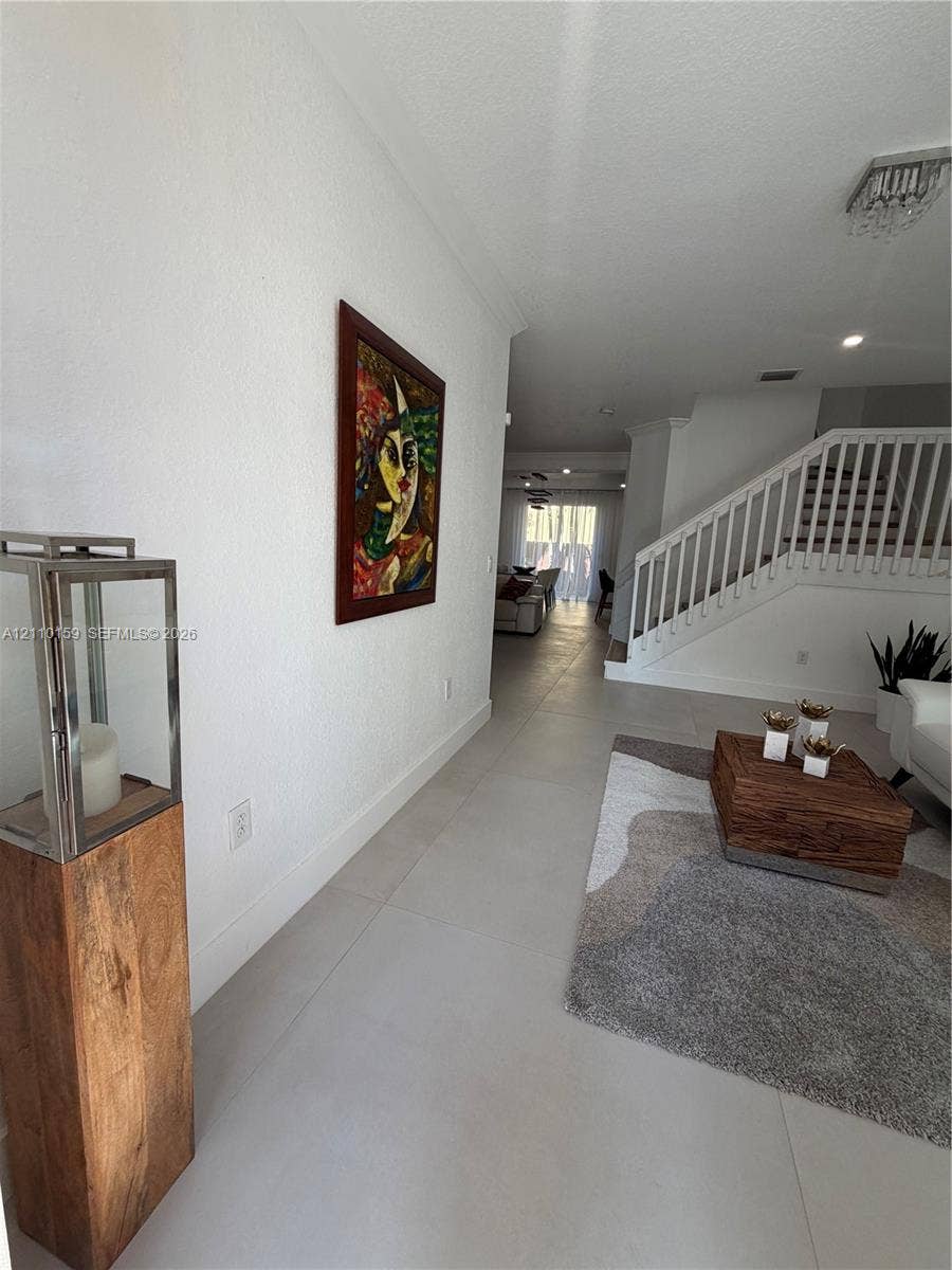 Interior area featuring large-format tile flooring, white wall finishes, a built-in staircase with a wooden handrail and white balusters, and recessed ceiling lighting