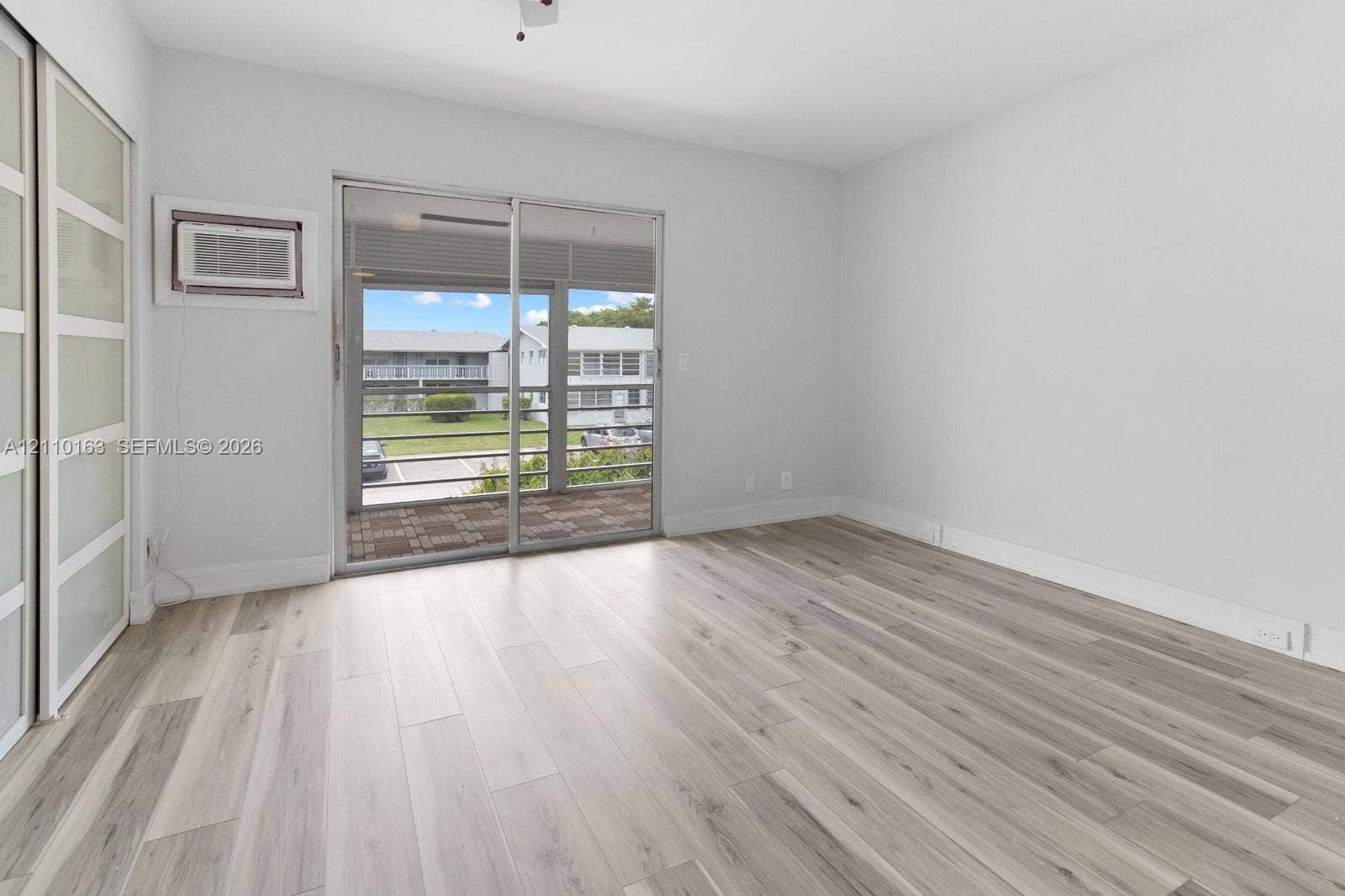 Neutral-toned wood-finish flooring, sliding glass patio door, frosted glass sliding closet doors, and attached balcony with railings