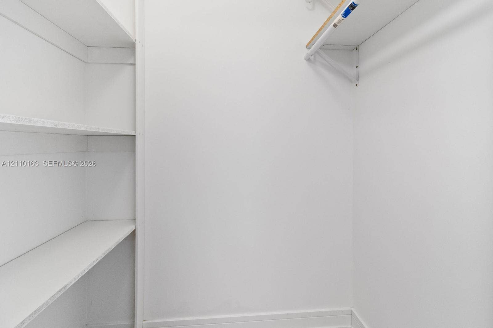Built-in white shelving unit featuring four storage levels, complemented by a white hanging rod and overhead shelf