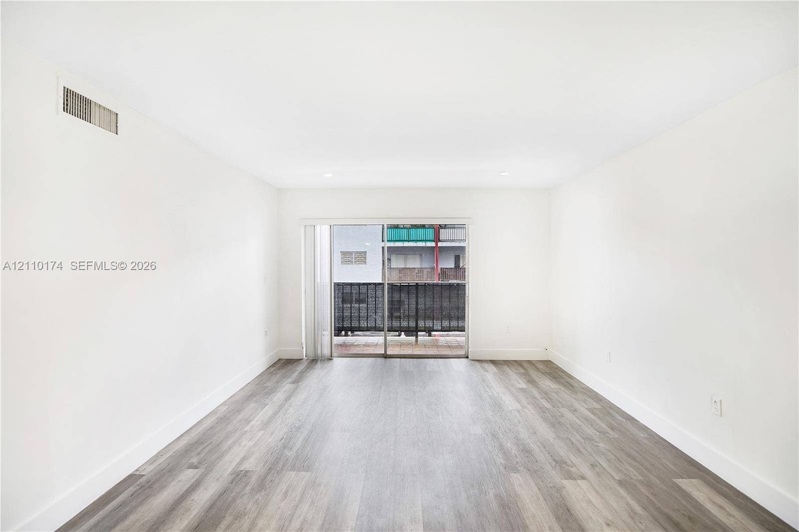 Interior space featuring wood-finish flooring, recessed lighting, and sliding glass doors with a metal railing