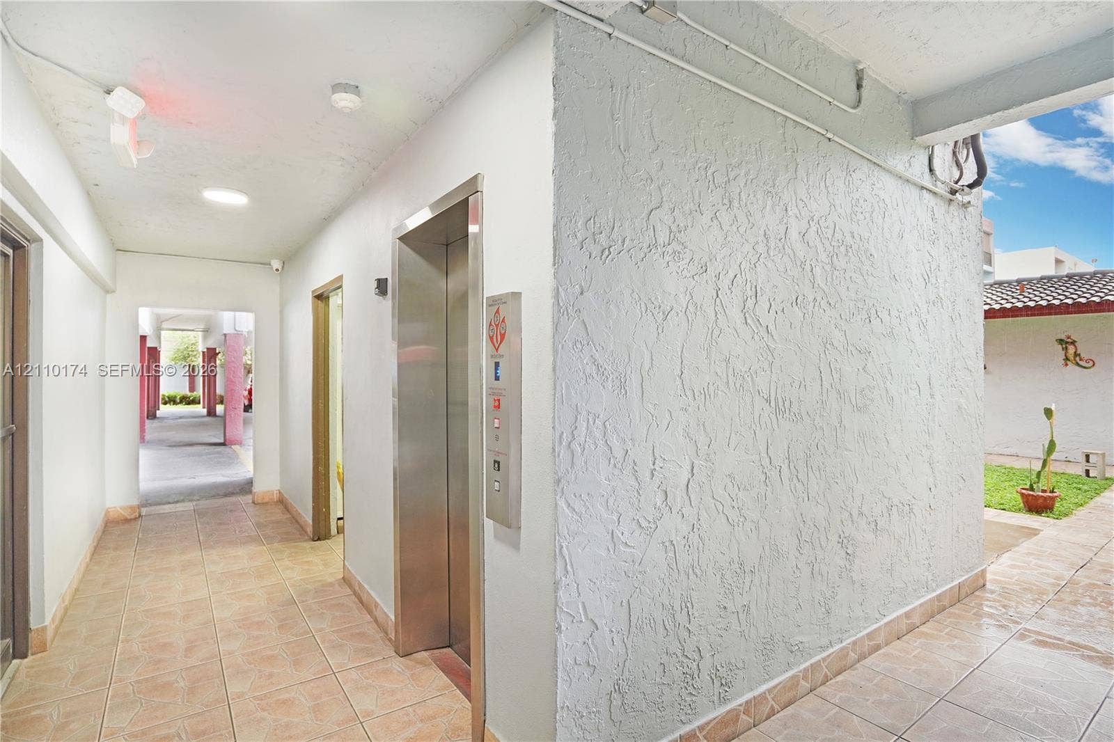 Elevator access area featuring textured wall finishes, tile flooring, and recessed ceiling lighting