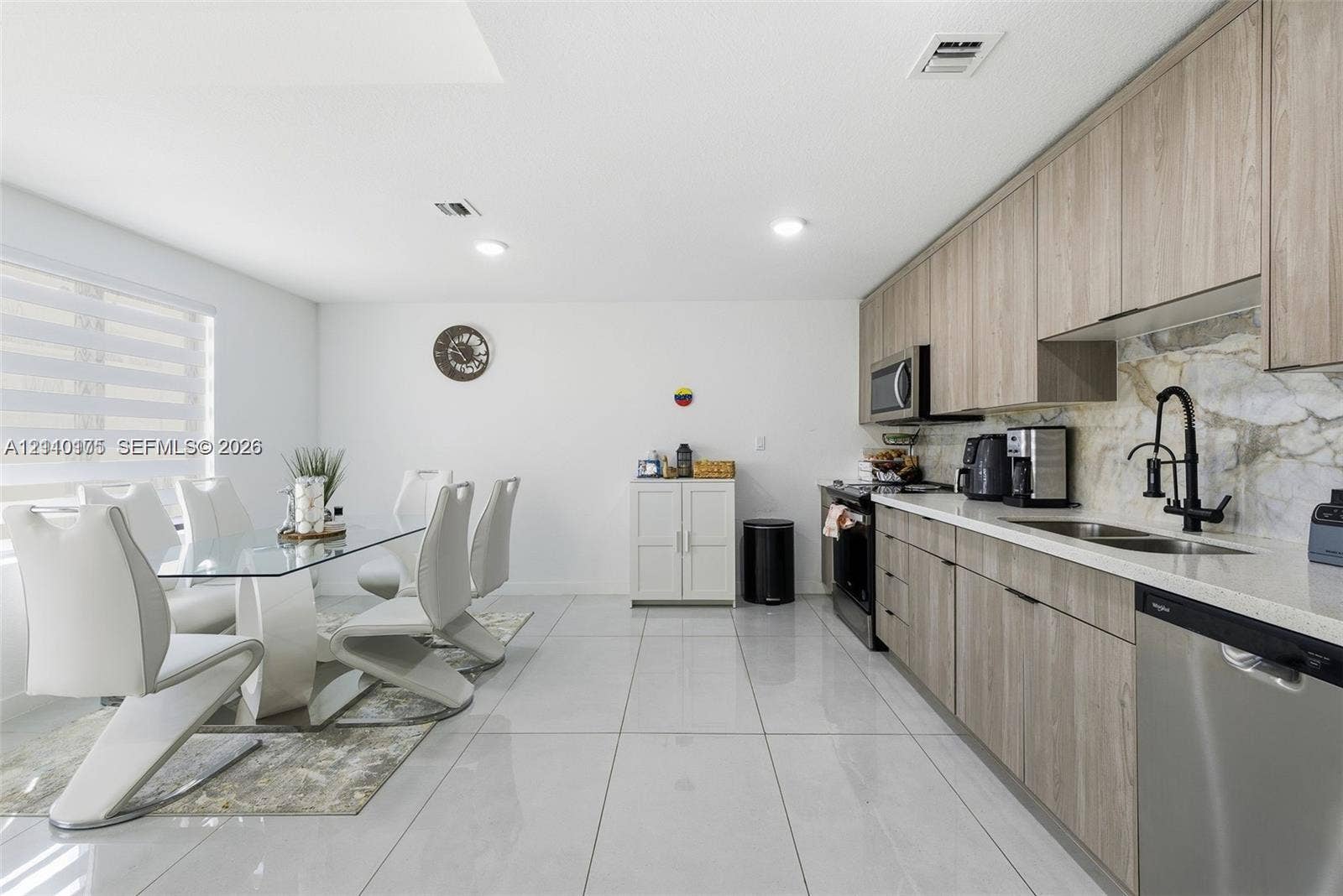 26122 SW 145th Court, #26122, Homestead, Homestead, FL 33032 Kitchen featuring wood-finish cabinetry, stone-patterned backsplash, light-colored stone countertops, stainless steel appliances, and large-format porcelain tile flooring