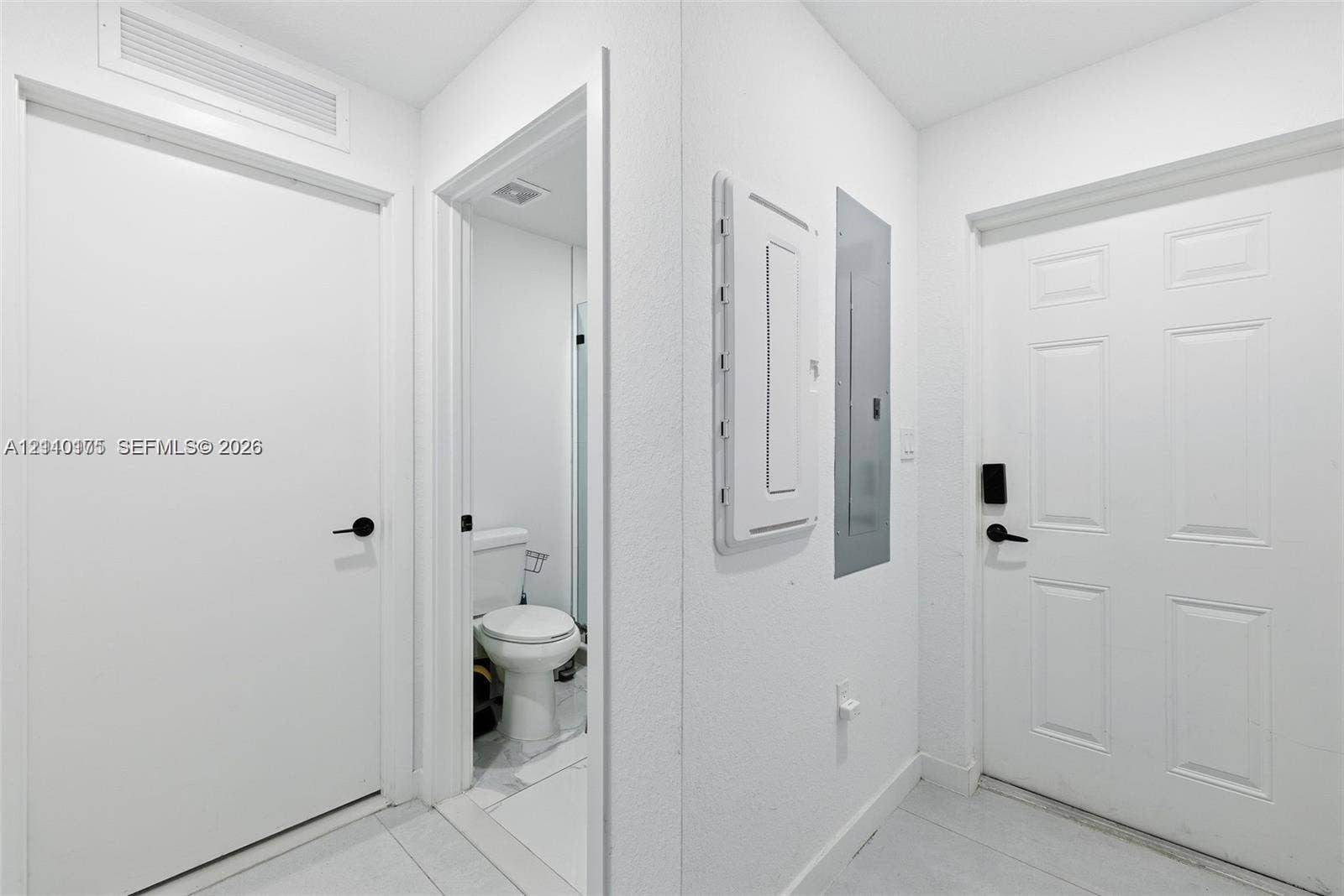 26122 SW 145th Court, #26122, Homestead, Homestead, FL 33032 Interior hallway featuring paneled doors with matte black hardware, ceramic tile flooring, and integrated electrical service panel