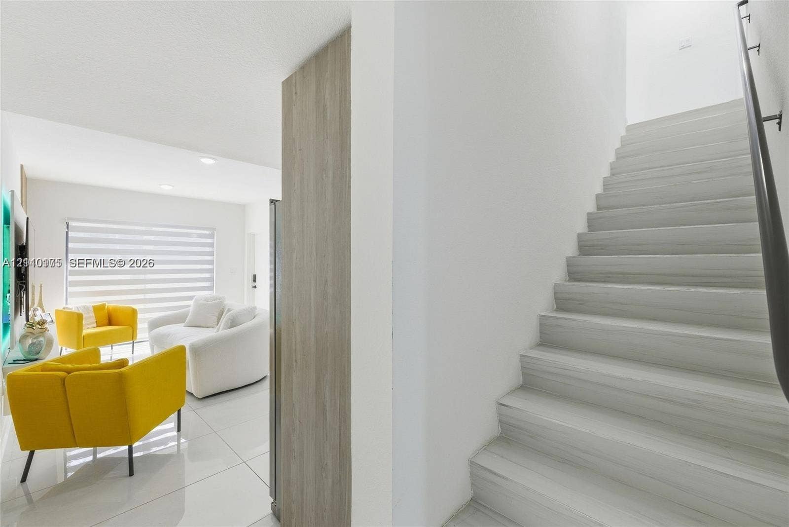 26122 SW 145th Court, #26122, Homestead, Homestead, FL 33032 Staircase featuring wood-finish treads and a dark metal handrail, complemented by large-format tile flooring and a neutral color palette