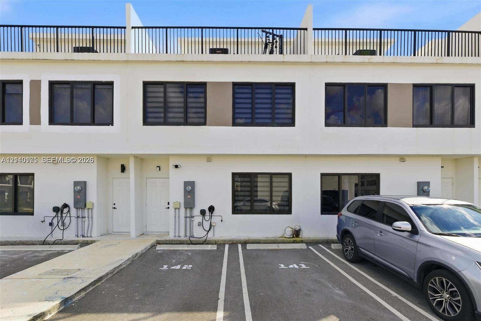 26122 SW 145th Court, #26122, Homestead, Homestead, FL 33032 Contemporary two-story exterior with light-toned stucco facade, dark-framed windows, and private rooftop terrace featuring metal railing