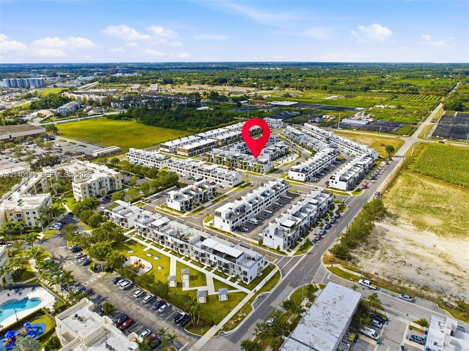 26122 SW 145th Court, #26122, Homestead, Homestead, FL 33032 Aerial perspective of multi-level residential complex featuring paved surface parking, organized pedestrian walkways, landscaped common green spaces, and community swimming pool