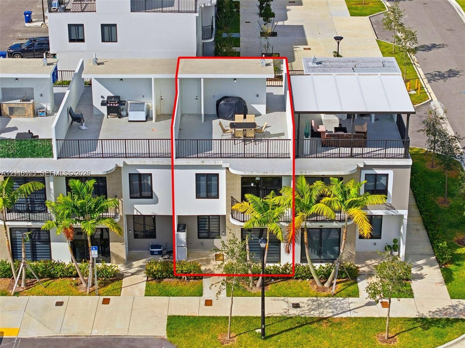 26122 SW 145th Court, #26122, Homestead, Homestead, FL 33032 Multi-level townhome featuring a rooftop terrace with metal railings, glass sliding doors, dark-framed windows, and a paved ground-level entry area