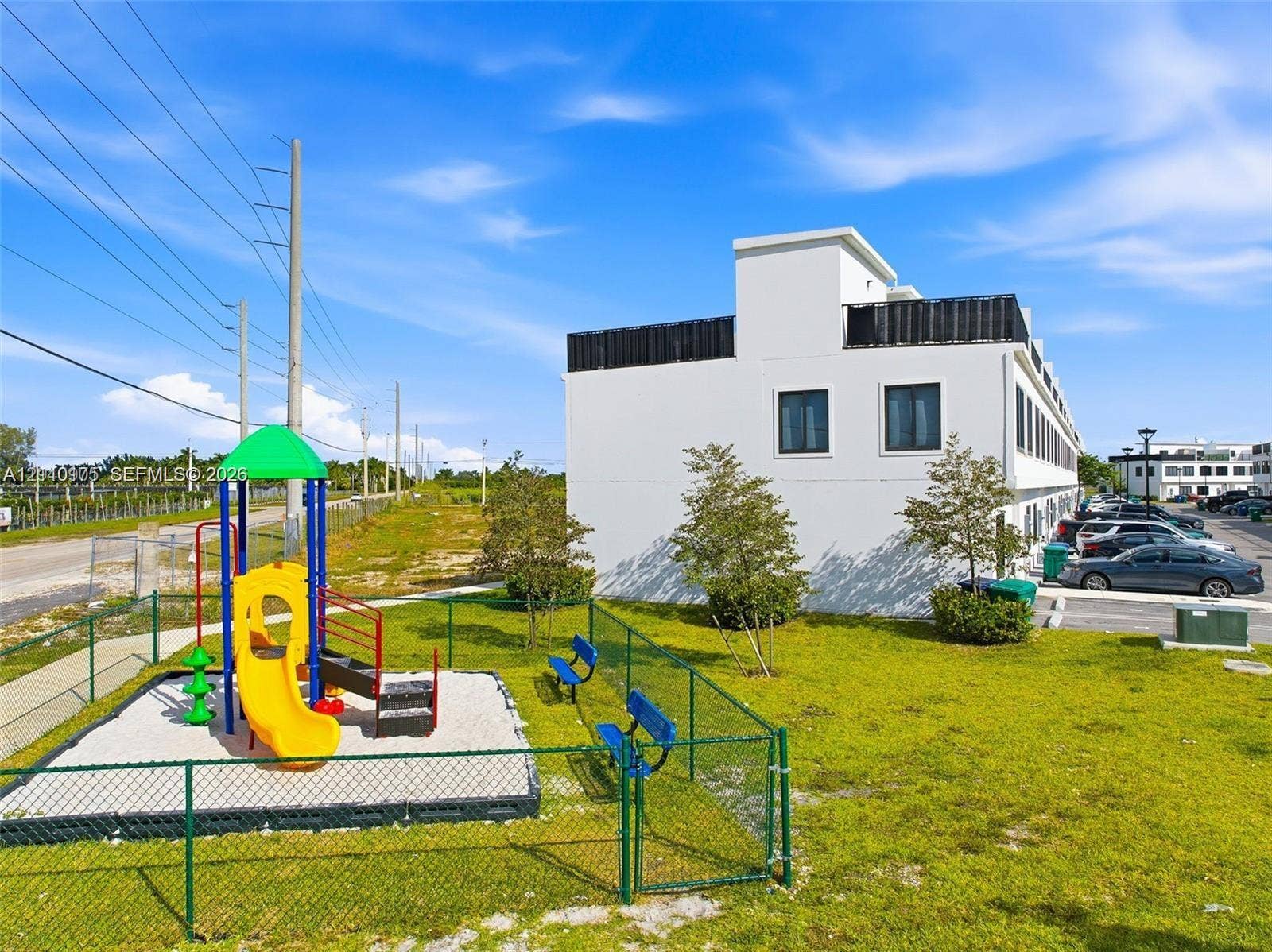 26122 SW 145th Court, #26122, Homestead, Homestead, FL 33032 Exterior grounds featuring a fenced-in playground area with a slide and climbing structure, green space, and surface parking