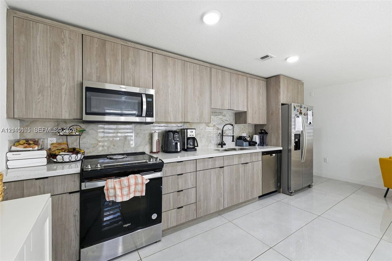 26122 SW 145th Court, #26122, Homestead, Homestead, FL 33032 Kitchen featuring wood-finish cabinetry, stainless steel appliances, stone-surface backsplash, and large-format tile flooring