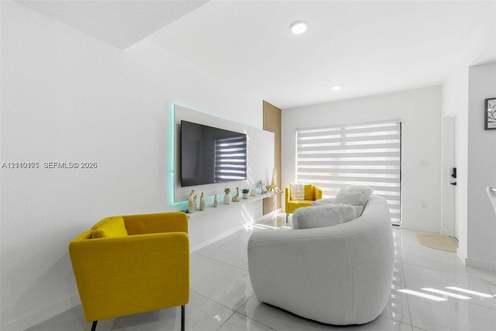 26122 SW 145th Court, #26122, Homestead, Homestead, FL 33032 Large-format porcelain tile flooring, built-in media wall with recessed accent lighting, floor-to-ceiling wooden wall paneling, and adjustable horizontal window shades