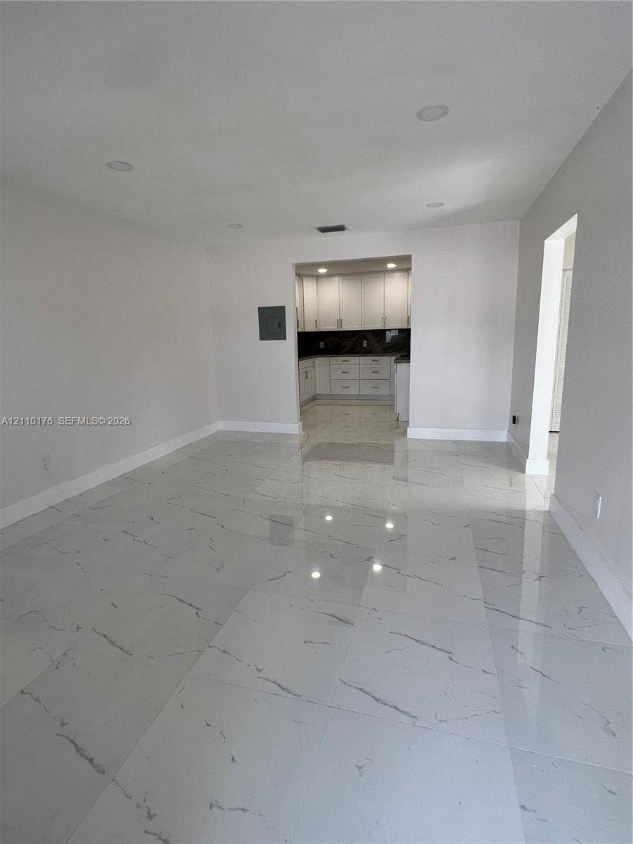 Large-format tile flooring with veining detail, recessed lighting, and white cabinetry