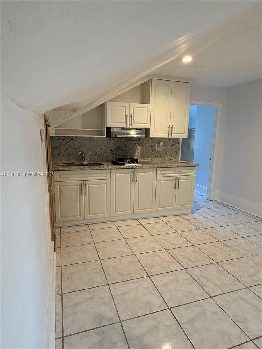 Kitchen featuring white shaker-style cabinetry, stone-finish countertops, stainless steel sink, gas cooktop, and tile flooring