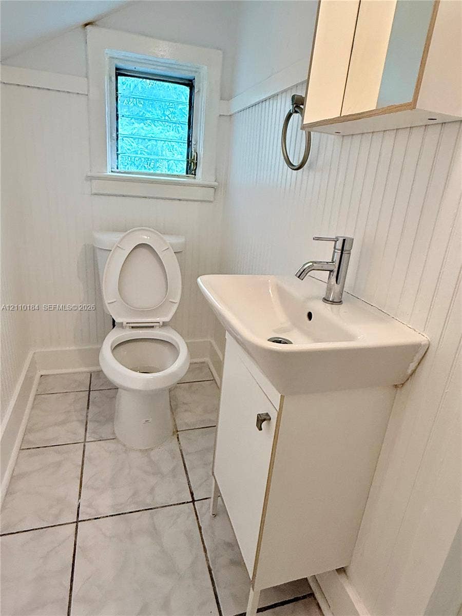 Bathroom featuring beadboard wall paneling, tile flooring, pedestal sink with a chrome faucet, and a wall-mounted medicine cabinet