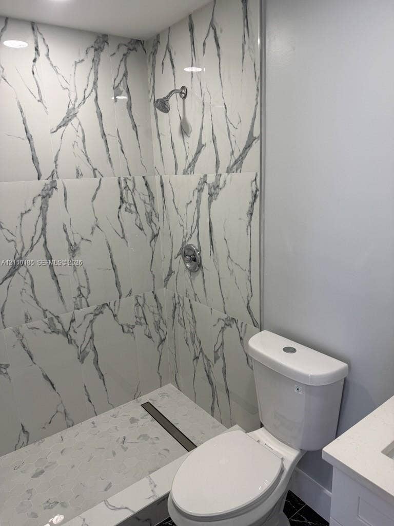 2596 Rosehaven Road, #2, West Palm Beach, West Palm Beach, FL 33415 Shower enclosure featuring large-format veined tile surround, chrome shower head, integrated linear drain, and a white finish toilet