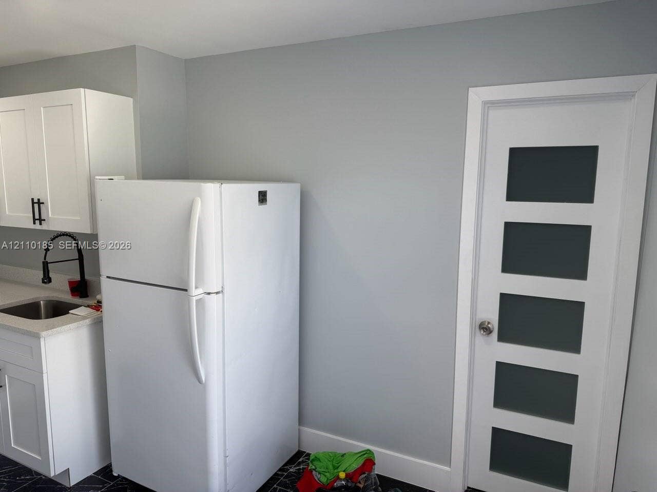 2596 Rosehaven Road, #2, West Palm Beach, West Palm Beach, FL 33415 Kitchen featuring white shaker-style cabinetry, a high-arc matte black faucet, a stone-composite countertop, and a five-panel door with frosted glass inserts