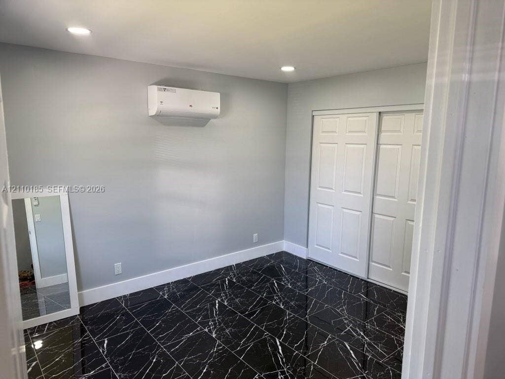 2596 Rosehaven Road, #2, West Palm Beach, West Palm Beach, FL 33415 Interior space featuring high-gloss dark stone-finish tile flooring, a wall-mounted ductless mini-split climate control system, recessed ceiling lighting, and a white sliding-panel closet