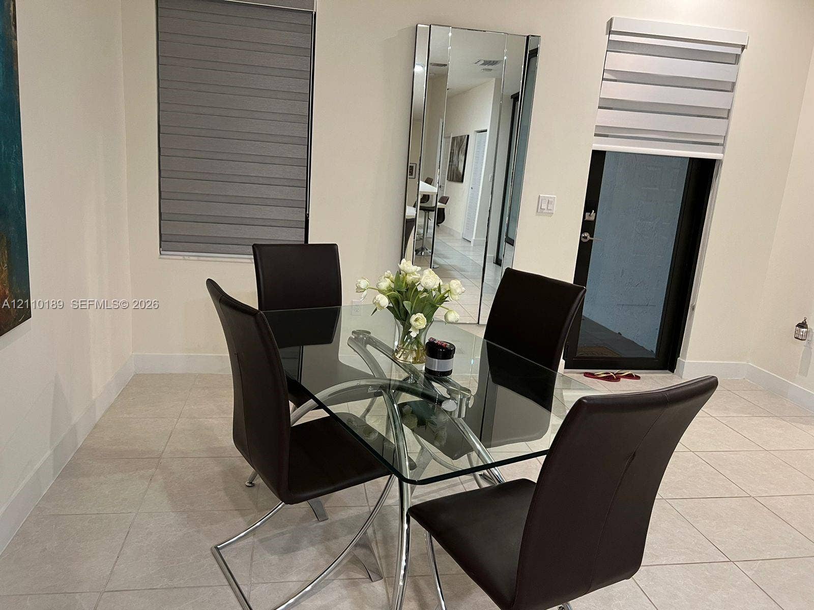 Neutral-toned floor tiles, floor-to-ceiling wall mirror, and dual-layered window treatments
