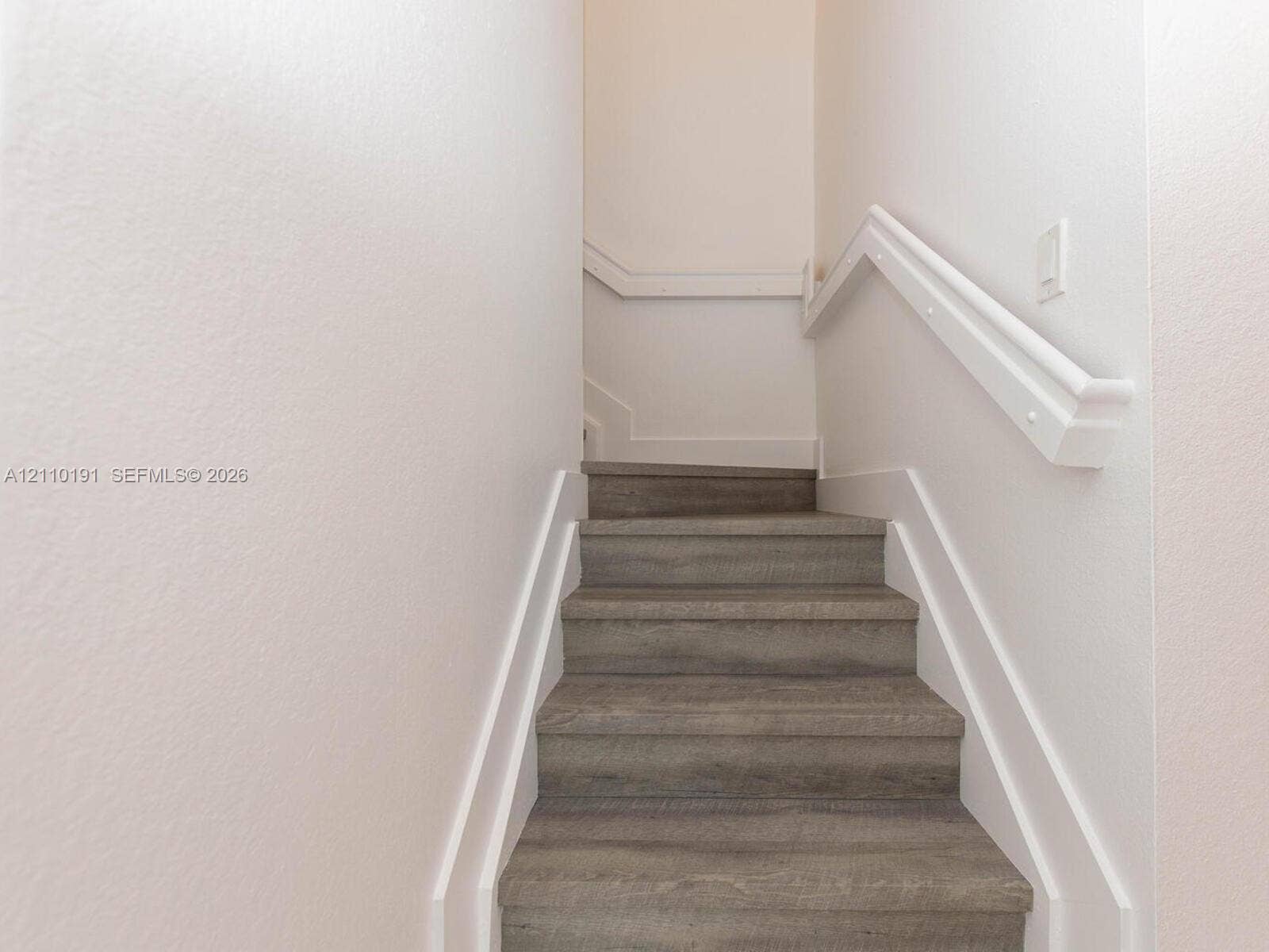 8999 NW 107 Court, #218-1, Miami, Miami, FL 33178 Staircase featuring wood-finish treads, crisp white trim, and a matching handrail