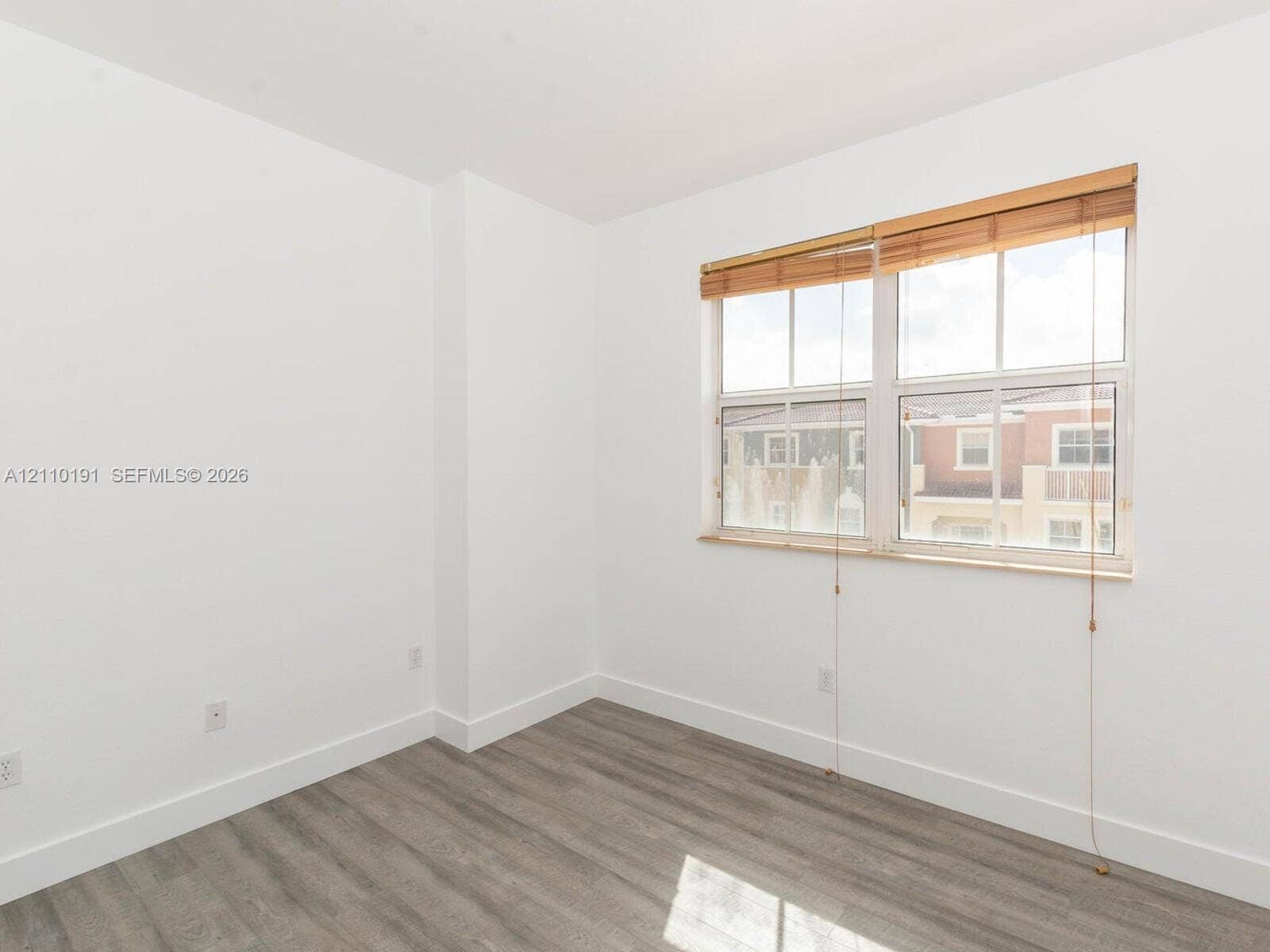 8999 NW 107 Court, #218-1, Miami, Miami, FL 33178 Neutral-toned walls paired with wood-finish flooring and a multi-pane window featuring installed wood blinds