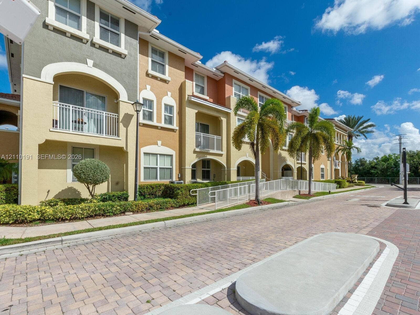 8999 NW 107 Court, #218-1, Miami, Miami, FL 33178 Multi-story exterior featuring a stucco facade, arched architectural details, private balconies with metal railings, and unit-specific concrete ramps