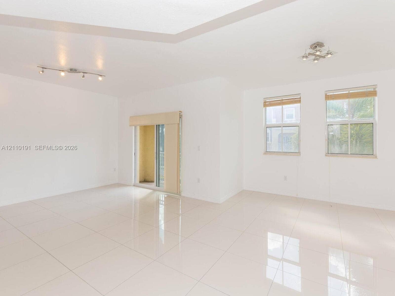 8999 NW 107 Court, #218-1, Miami, Miami, FL 33178 Open-concept space featuring polished ceramic tile flooring, recessed tray ceiling, multi-light track fixtures, and dual-pane windows