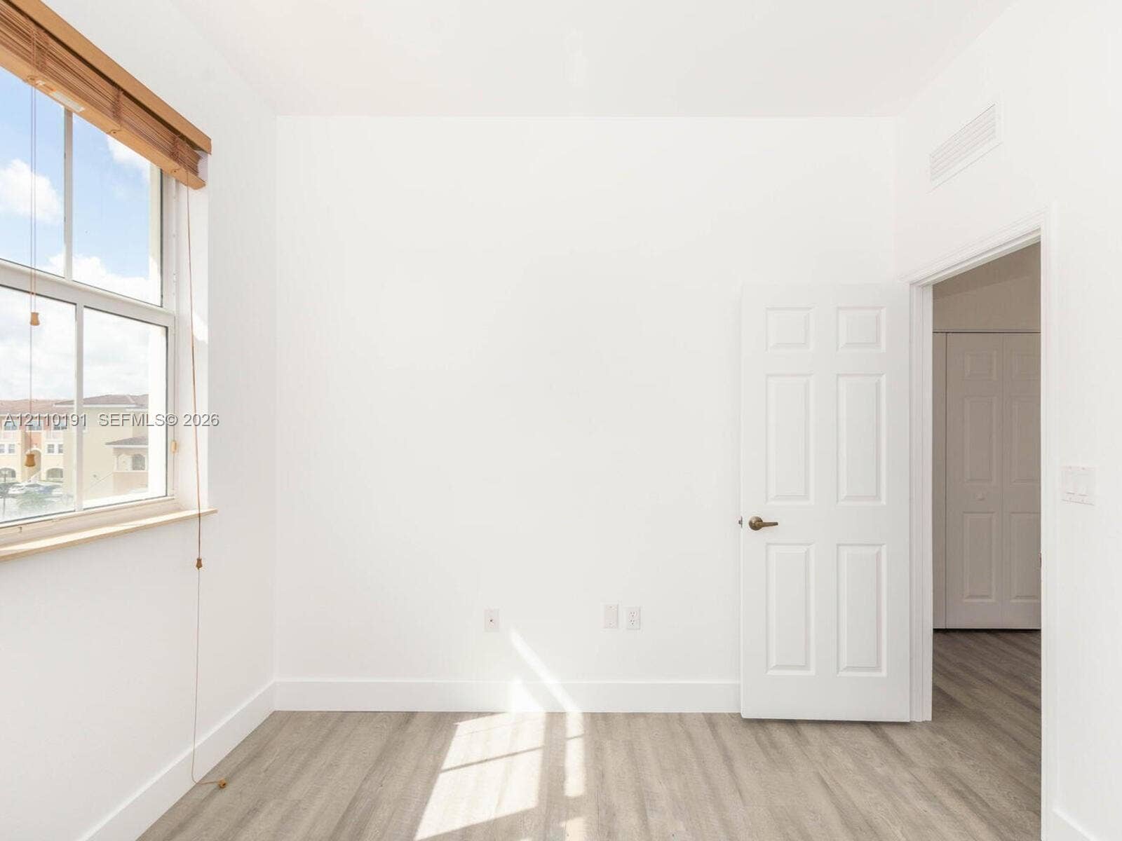 8999 NW 107 Court, #218-1, Miami, Miami, FL 33178 Wood-finish flooring, multi-pane window with wood-trim framing, six-panel interior door, and smooth-finish walls