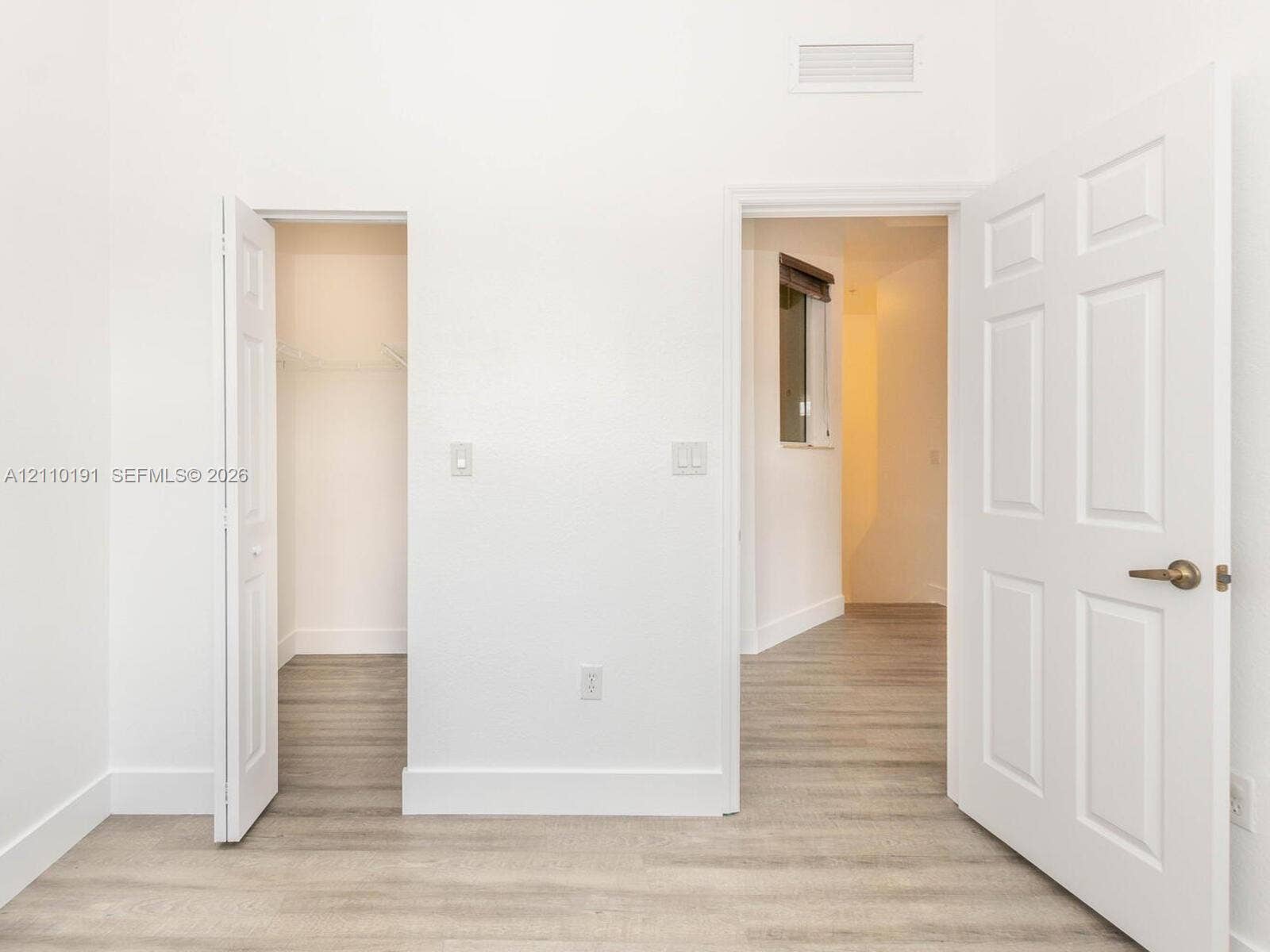 8999 NW 107 Court, #218-1, Miami, Miami, FL 33178 Room featuring wood-finish flooring, white walls, six-panel interior doors, and a built-in closet with wire shelving
