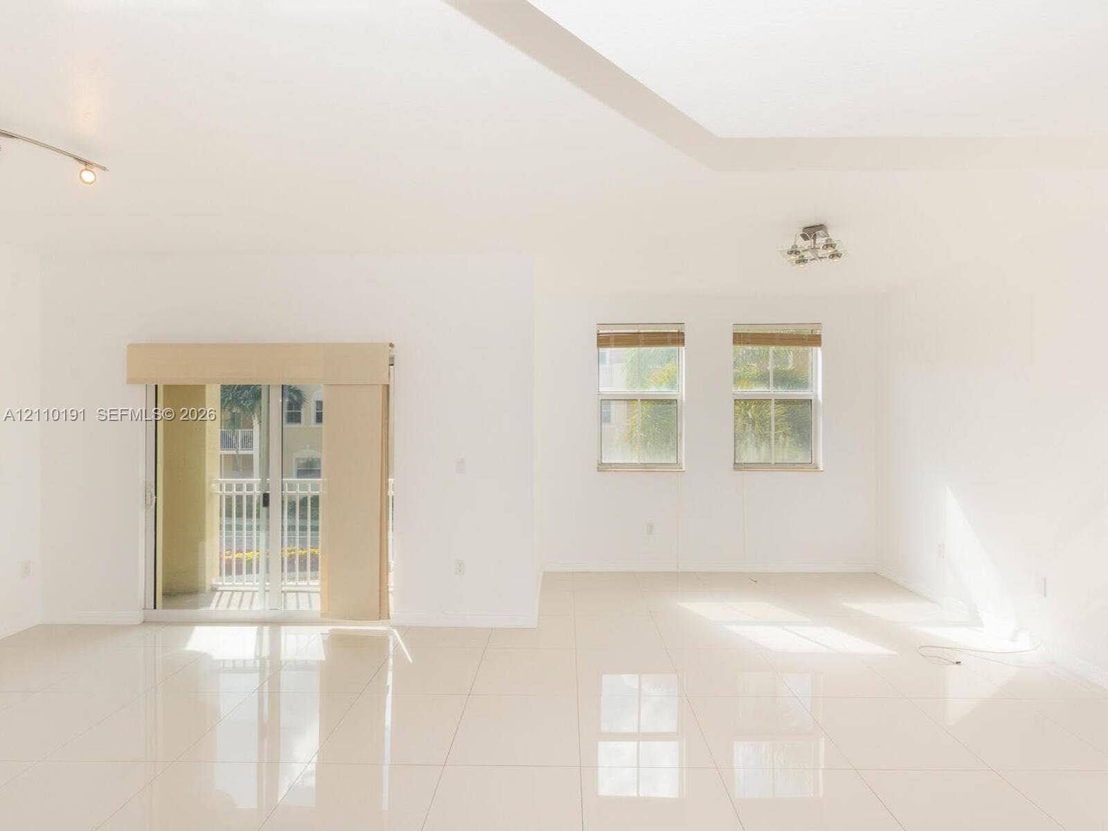 8999 NW 107 Court, #218-1, Miami, Miami, FL 33178 Open floor plan featuring oversized tile flooring, recessed tray ceiling detailing, sliding glass doors to a private balcony, and dual-pane windows