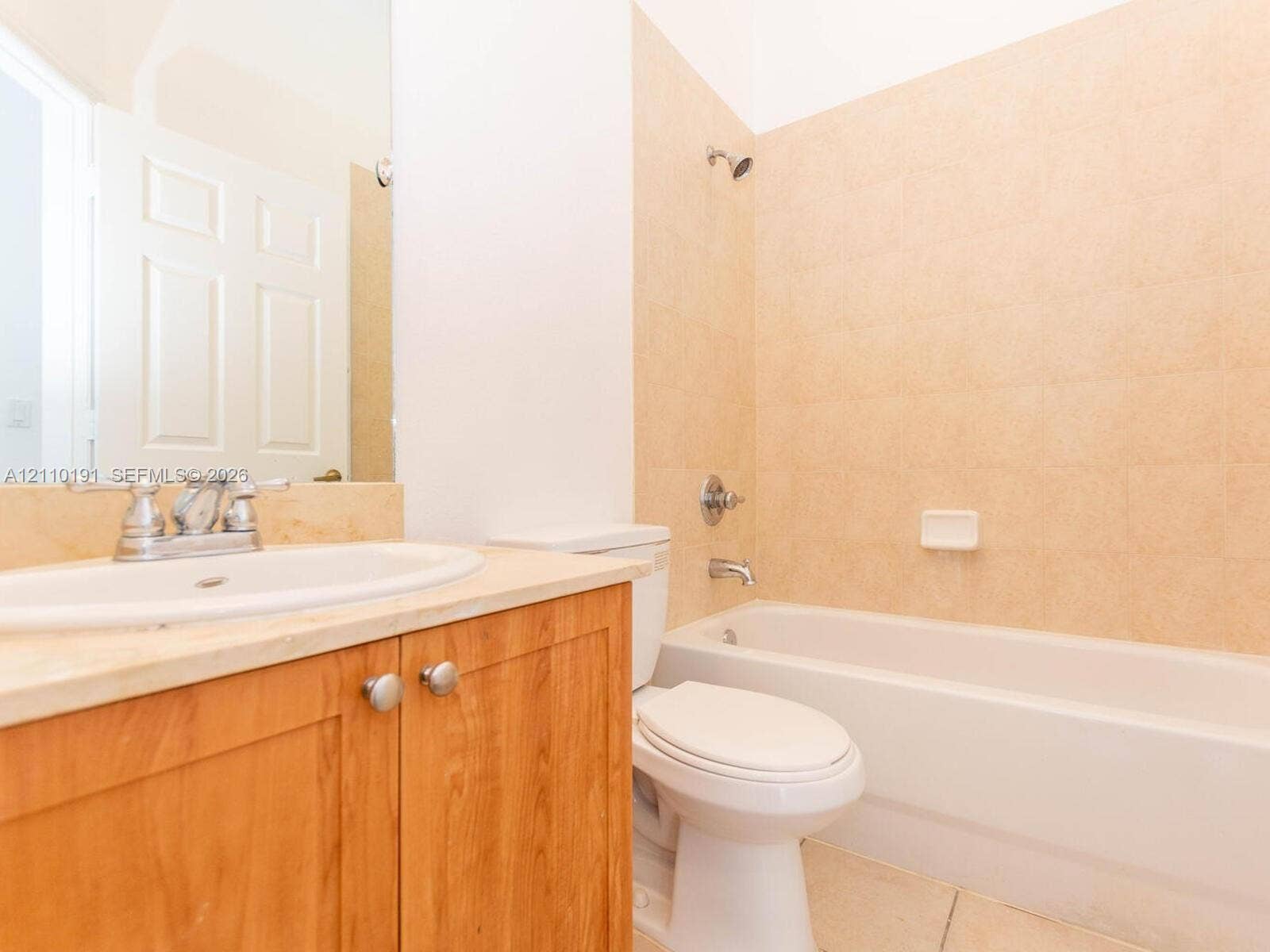 8999 NW 107 Court, #218-1, Miami, Miami, FL 33178 Bathroom featuring a wood-finish vanity with a stone countertop, an integrated drop-in sink, a wall-mounted mirror, and a bathtub with tile surround